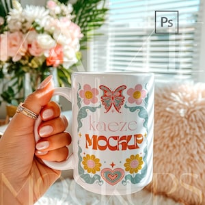 Trendy hand held mug mockup showing a 15oz ceramic mug with colorful retro floral design applied. Natural lifestyle composition with realistic grip, highlights, and ceramic reflections. Editable mug body allows seamless artwork replacement in Photoshop or Canva. Ideal mug mockups for creative sellers and modern 15oz mug mockup displays.