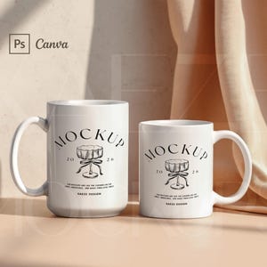 Puede incluir: Dos tazas de cerámica blancas de diferentes tamaños. Cada taza tiene un asa y un diseño gráfico negro con la palabra "MOCKUP" y el texto "KAZE DESIGN". El fondo incluye una tela beige y una sombra.