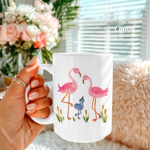 Trendy hand held mug mockup featuring a 15oz ceramic coffee mug with watercolor flamingo artwork example. Styled in a warm lifestyle scene with soft daylight and cozy textures. Fully editable mug body using Canva drag and drop template. High quality mug mockups ideal for artistic, colorful, and modern mug mockup presentations.
