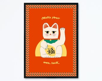 May include: A framed art print featuring a cartoon illustration of a white Maneki-neko cat with a raised paw. The cat is on a bright orange background with the text "Make your own luck" and a Japanese character. The frame is black.