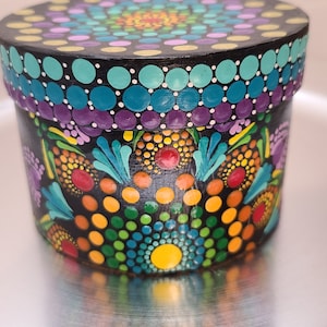 Caja de cartón pintada a mano en tonos morados, naranjas y arcoíris para guardar baratijas, organizar con estilo o regalar.
