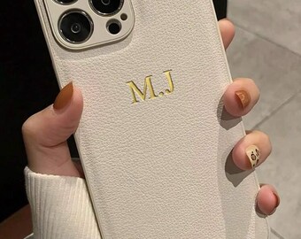 May include: White leather iPhone case with a gold monogram "M.J."