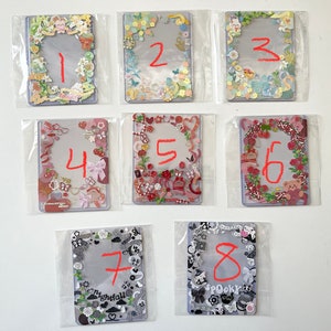 May include: Eight colourful cards with white borders and various decorative elements. Each card has a number written in red on the inside. The numbers are 1, 2, 3, 4, 5, 6, 7, and 8.
