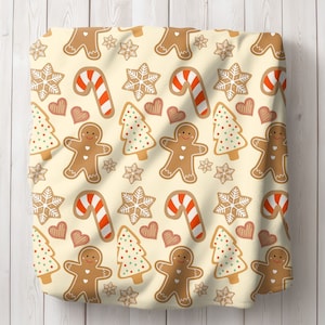 Puede incluir: Una tela de color crema con un patrón repetido de hombres de jengibre, bastones de caramelo, copos de nieve y árboles de Navidad. El patrón está en tonos de marrón, rojo, verde y blanco.