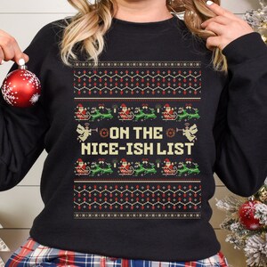 May include: Black Christmas jumper with a festive design featuring Santa Claus, reindeer, and the text "On the Nice-ish List".