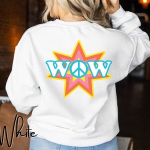 Puede incluir: Sudadera blanca con un gran diseño de estrella estrellada de colores con la palabra "WOW" y un signo de paz en el centro.