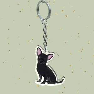 May include: Black chihuahua keychain with a silver key ring. The keychain is made of clear acrylic and features a cartoon illustration of a black chihuahua.