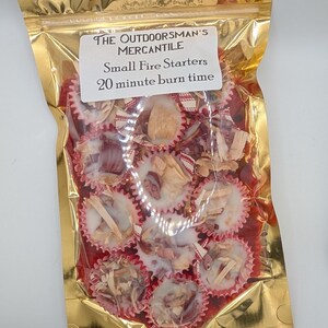 May include: A gold metallic bag containing small fire starters. The bag has a white label with the text "THE OUTDOORSMAN'S MERCANTILE Small Fire Starters 20 minute burn time". The fire starters are in red cupcake liners.