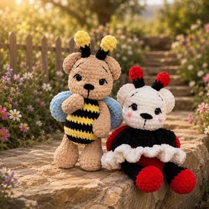Op de afbeelding: Twee handgemaakte gehaakte teddyberen. Eén is bruin met een bijenkostuum, inclusief gele en zwarte strepen en blauwe vleugels. De andere is wit met een lieveheersbeestjeskostuum, met rode en zwarte accenten. Ze zitten op een stenen oppervlak.
