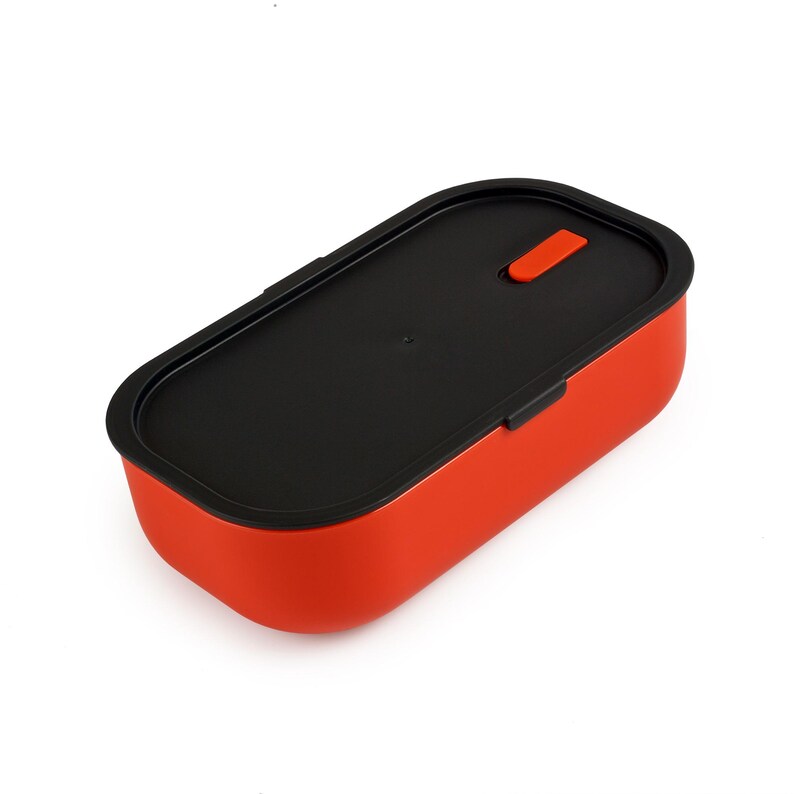 May include: A red rectangular lunch box with a black lid and an orange latch. The lunch box is made of a smooth, matte material. It is designed for carrying food items. The design is modern and minimalist, suitable for packed lunches.