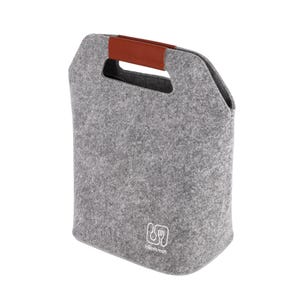 May include: A grey felt lunch bag with a brown leather handle. The bag has a rectangular shape with a cutout handle at the top. A white logo with a fork and spoon is visible on the front of the bag.
