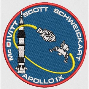 Könnte beinhalten: Gestickter Aufnäher mit dem Abzeichen der Apollo IX-Mission. Das Design zeigt eine Rakete, ein Raumschiff und eine gelbe Verbindungslinie auf blauem Hintergrund. Die Namen McDivitt, Scott und Schweickart sind zusammen mit "APOLLO IX" abgebildet.