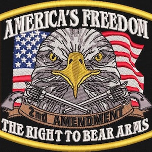 Könnte beinhalten: Gestickter Aufnäher mit einem Weißkopfseeadler, der die amerikanische Flagge und gekreuzte Pistolen zeigt. Der Aufnäher enthält den Text "AMERICA'S FREEDOM" und "2nd AMENDMENT THE RIGHT TO BEAR ARMS".