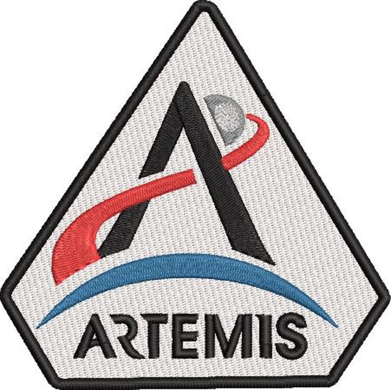 Pu&ograve; includere: Toppa ricamata con il logo Artemis. Il design include una forma a 'A' nera, una linea curva rossa, un arco blu e una sfera grigia. La parola 'ARTEMIS' &egrave; visualizzata in nero, sotto l'arco blu, all'interno di un triangolo bianco.