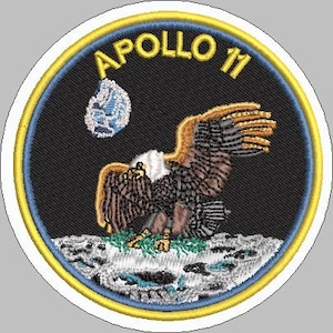 May include: Embroidered patch featuring the Apollo 11 mission emblem. The design includes a bald eagle landing on the moon, with the Earth in the background. The text "APOLLO 11" is arched across the top in yellow.