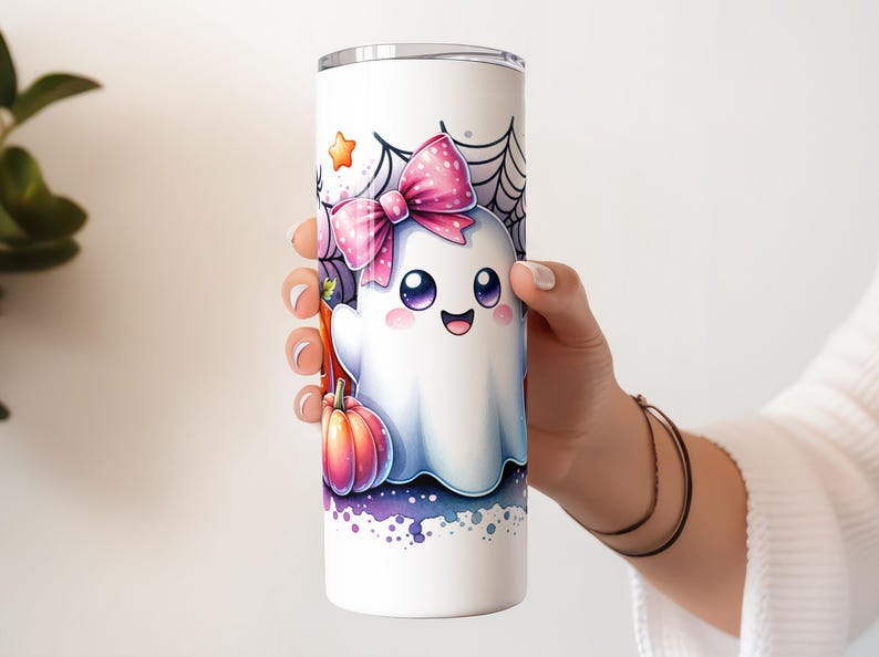 Pu&ograve; includere: Un bicchiere in acciaio inossidabile bianco con un fantasma dei cartoni animati che indossa un fiocco rosa e tiene una zucca. Il fantasma ha occhi grandi e un'espressione felice. Lo sfondo &egrave; un design ad acquerello viola e bianco con una ragnatela.