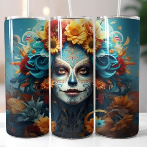 May include: A stainless steel tumbler with a colourful design featuring a sugar skull with blue hair and floral accents. The skull has intricate details and is surrounded by vibrant flowers.