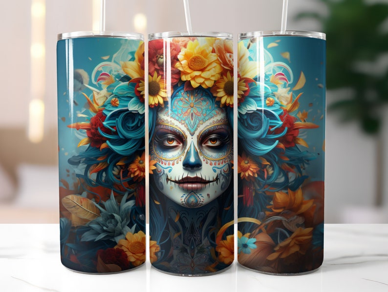 May include: A stainless steel tumbler with a colourful design featuring a sugar skull with blue hair and floral accents. The skull has intricate details and is surrounded by vibrant flowers.