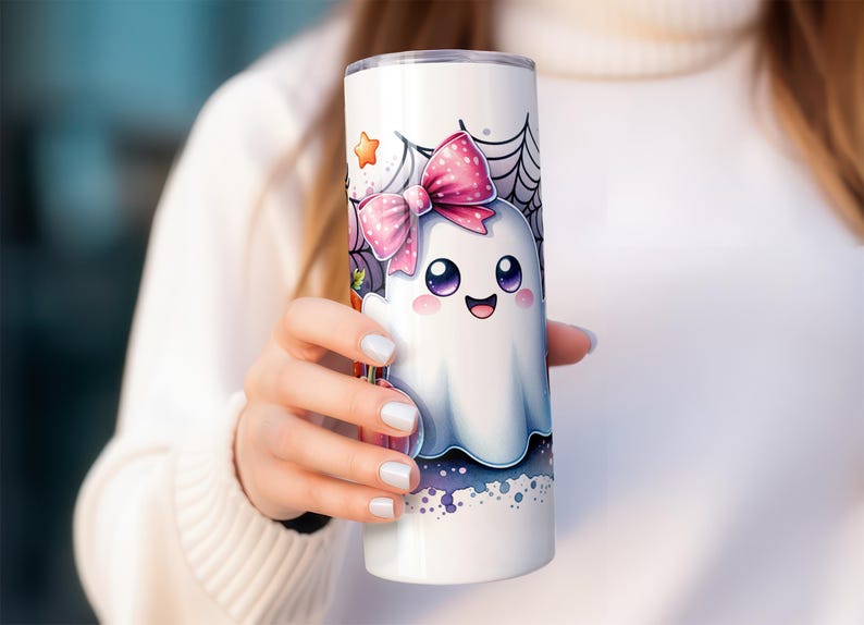 Pu&ograve; includere: Un bicchiere in acciaio inossidabile bianco con un fantasma dei cartoni animati che indossa un fiocco rosa e circondato da ragnatele. Il fantasma ha occhi grandi e un'espressione felice.