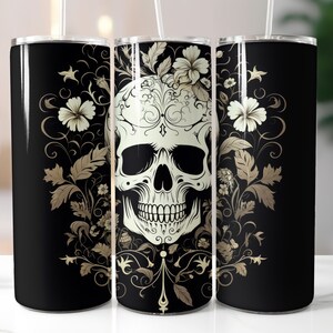 May include: A black tumbler with a white skull design, surrounded by floral and ornamental details in gold. The design is repeated around the tumbler. A straw is inserted in the lid.