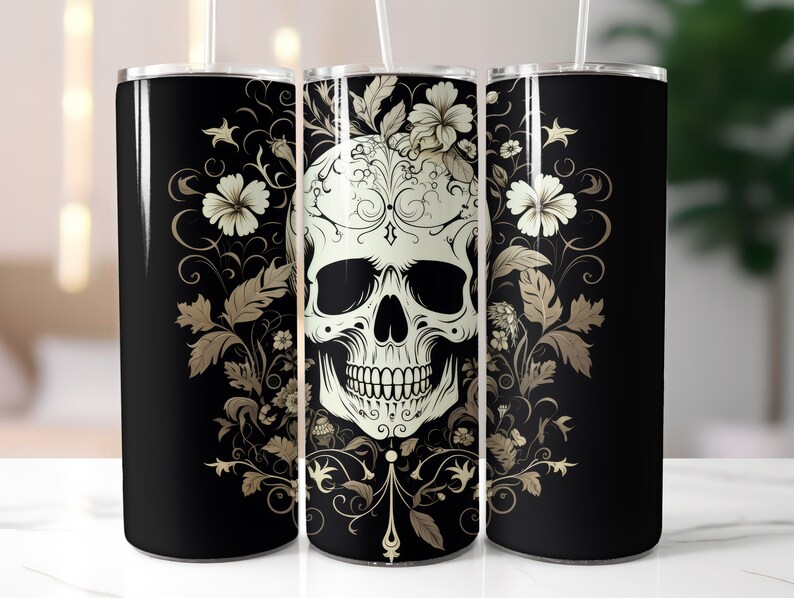 May include: A black tumbler with a white skull design, surrounded by floral and ornamental details in gold. The design is repeated around the tumbler. A straw is inserted in the lid.