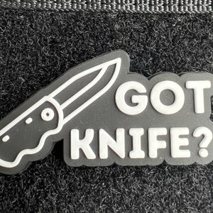 Könnte beinhalten: Schwarz-weißes Patch mit einem Messerumriss und dem Text "GOT KNIFE?" in Weiß.