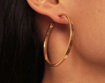 May include: Gold hoop earrings with a diameter of 1.4 inches. The earrings are 6.57 grams each.