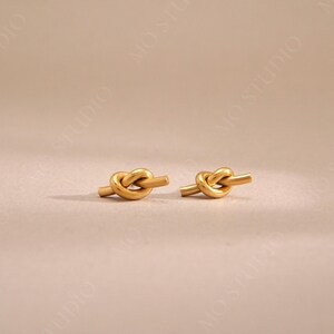 May include: A pair of gold knot-shaped earrings. The earrings are simple and elegant, and would make a great gift for any occasion.