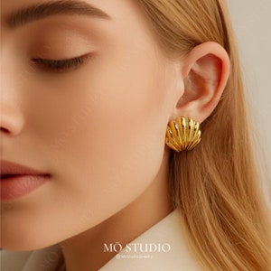 May include: Gold-toned shell-shaped earrings. The earrings are a simple, elegant design.