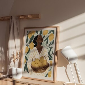 May include: A framed illustration of a person standing in a lemon grove, holding a basket of lemons. The person is wearing a white and yellow striped shirt and has dark hair. The background is a green and yellow color scheme.