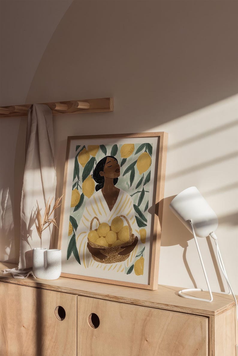 May include: A framed illustration of a person standing in a lemon grove, holding a basket of lemons. The person is wearing a white and yellow striped shirt and has dark hair. The background is a green and yellow color scheme.