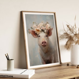 Puede incluir: Una pintura enmarcada de un cerdo con una corona de flores rosas y blancas. El cerdo mira directamente al espectador con una expresi&oacute;n suave. El fondo es de un azul suave.