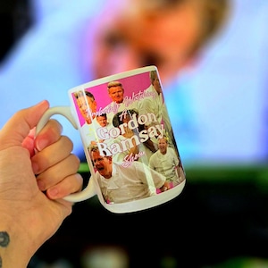 May include: White ceramic mug with a pink background and a collage of photos of Gordon Ramsay. The text on the mug reads "Probably Watching A Gordon Ramsay Show".
