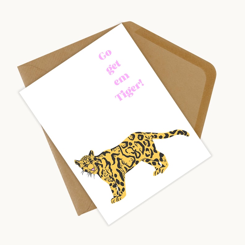 May include: A white greeting card with a yellow and black leopard illustration and the text "Go get em Tiger!" in pink. The card is inside a brown envelope.