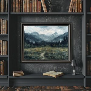 K&ouml;nnte beinhalten: Ein gerahmtes Landschaftsbild mit einer Bergkette und einem Wald im Vordergrund. Das Bild ist in einem dunklen Holzrahmen gefasst und h&auml;ngt an einer dunklen Wand.