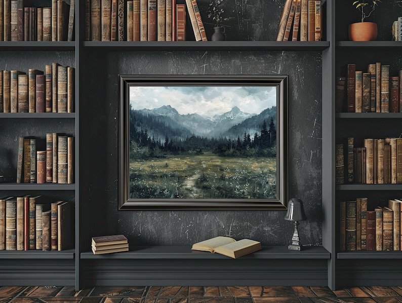 K&ouml;nnte beinhalten: Ein gerahmtes Landschaftsbild mit einer Bergkette und einem Wald im Vordergrund. Das Bild ist in einem dunklen Holzrahmen gefasst und h&auml;ngt an einer dunklen Wand.