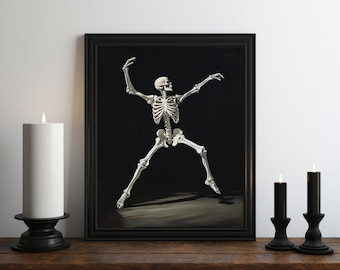 May include: A black framed print of a white skeleton dancing against a black background. The skeleton is posed with one arm raised and the other extended to the side. The print is displayed on a wooden shelf with two black candlesticks and white candles.