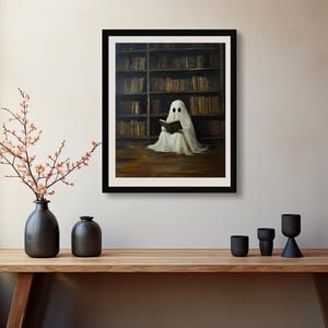 May include: A white ghost figure sitting in a library, reading a book. The ghost is wearing a white sheet and has two black eyes. The library is filled with bookshelves and books.