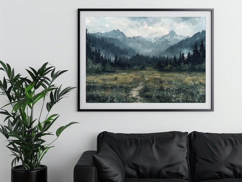 K&ouml;nnte beinhalten: Ein gerahmter Druck einer nebligen Berglandschaft mit einem Pfad, der durch ein Feld mit Wildblumen f&uuml;hrt. Die Berge sind in einem tiefen Blaugrau gehalten, und der Himmel ist hellblau mit wei&szlig;en Wolken. Der Druck ist in einem schwarzen Rahmen.
