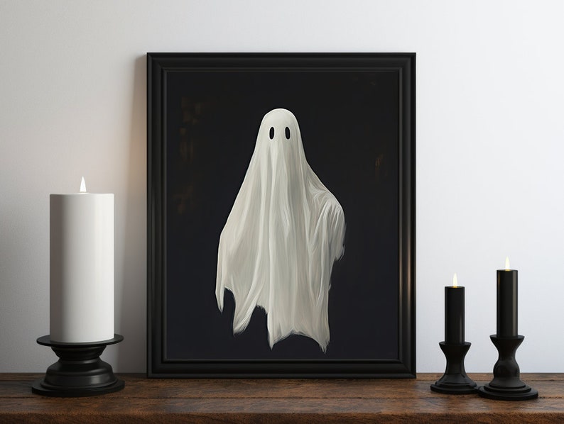 Peut inclure: Une illustration encadr&eacute;e en noir et blanc d'un fant&ocirc;me avec un drap blanc, sur un fond sombre. Le cadre est noir et l'image est sur une surface en bois avec deux chandeliers noirs et des bougies blanches.