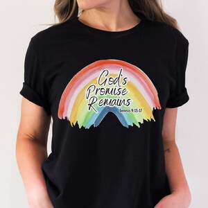 Pu&ograve; includere: Maglietta nera con una grafica arcobaleno e il testo "God's Promise Remains" con il versetto biblico Genesi 9:15-17.