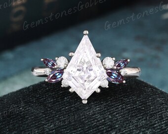 May include: A silver engagement ring with a large, clear, kite-shaped diamond center stone. The band is adorned with smaller diamonds and purple gemstones.