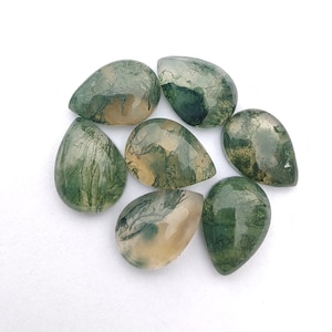 Puede incluir: Siete cabujones de ágata verde y blanca en forma de lágrima. Los cabujones tienen una apariencia translúcida y nublada con patrones verdes y blancos.