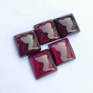 May include: Five square-shaped, deep red gemstones with a glossy finish. The gemstones are arranged in a staggered pattern.