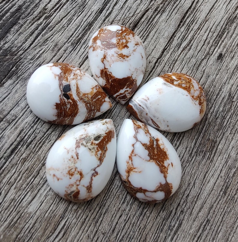 Puede incluir: Cinco cabujones en forma de l&aacute;grima de color blanco y marr&oacute;n con un patr&oacute;n de m&aacute;rmol.