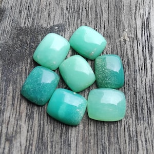 May include: A collection of seven smooth, polished, rectangular gemstones in varying shades of mint, seafoam, and forest green. Each stone features a rounded, cabochon-style top with a glossy finish, displaying unique natural color gradients.