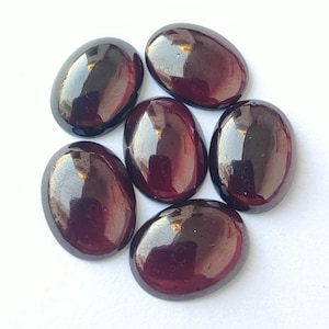 Puede incluir: Seis piedras preciosas ovaladas de color rojo oscuro con un acabado brillante. Las piedras preciosas est&aacute;n dispuestas en forma circular.