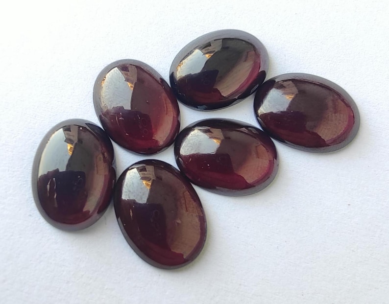 Puede incluir: Seis piedras preciosas ovaladas de color p&uacute;rpura oscuro con un acabado brillante.