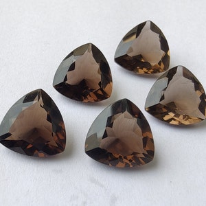 May include: Five triangular smoky quartz gemstones, each with a faceted cut and a dark brown color.