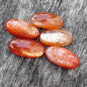 K&ouml;nnte beinhalten: Sechs glatte, ovale geschliffene Sunstone-Steine in Orange- und Goldt&ouml;nen mit einem schimmernden, irisierenden Finish.